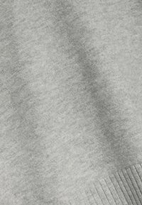 Tissu gris clair avec une texture douce et une ombre diagonale subtile, présentant un bord côtelé dans le coin inférieur droit.