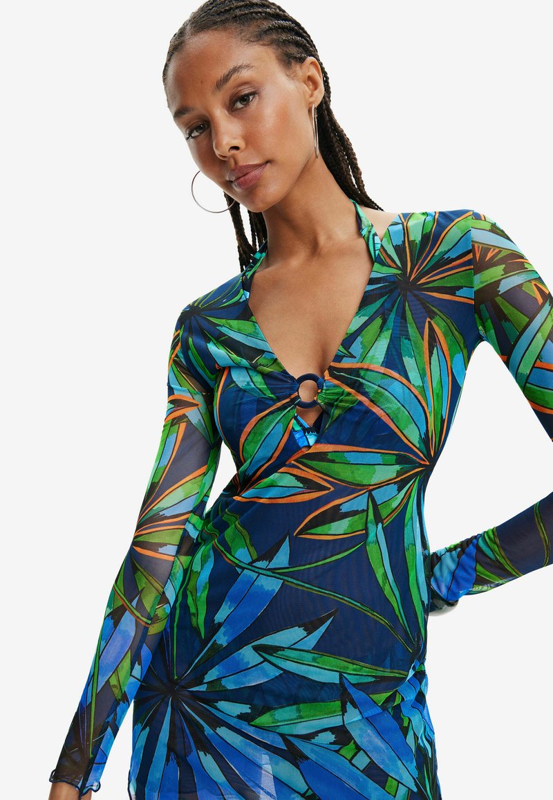 Langsleeve jurk met een multicolore bladprint in groen, blauw en oranje, met een V-hals en een ronde uitsnijding bij de borst.
