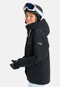 Black ski jacket with a hood, featuring zippered pockets, logo accents, and textured fabric. Worn with black gloves and goggles.
