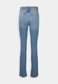 Jeans de denim azul desbotado com corte reto, design de cinco bolsos e costuras forradas. Apresenta um patch de marca em couro na cintura.