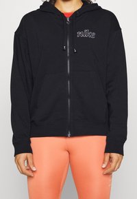 Sweat à capuche zippé noir en tissu doux, doté d'une poche kangourou, d'une capuche avec cordon de serrage, et d'un logo brodé sur la poitrine.