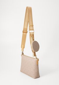 Beige crossbody bag with textured logo pattern, gold hardware, and a detachable round coin pouch. Adjustable strap features embossed branding.