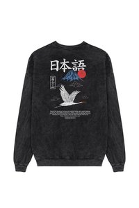 Fekete kereknyakú pulóver, amelyen egy grafikai ábrázolás látható a Fuji-hegyről, egy piros napról, felhőkről és egy fehér darúról, japán szöveggel és részletekkel az alján.