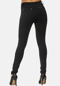 Zwarte skinny jeans met een hoge taille, voorzien van twee achterzakken en subtiele hardwareaccenten. Gladde textuur en een getailleerde pasvorm.