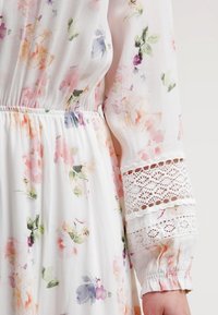 Vestido ligero con estampado floral en suaves colores pastel. Presenta una cintura fruncida y mangas con puntilla para un detalle adicional.