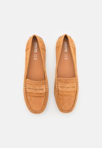 Tan suède instappers met een moccasin-stijl ontwerp, met gestikte details en een penny loafer band over de voorkant.