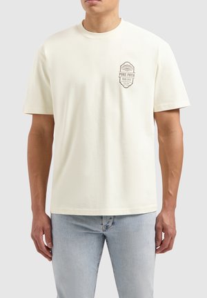 Cream cotton t-shirt with short sleeves, round neck, and front graphic in brown featuring "PURE PATH" and badge design. Standard fit.