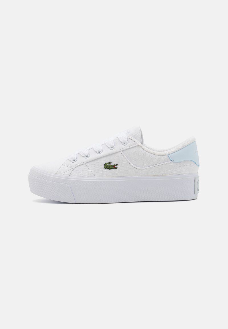 Basket basse blanche avec semelle épaisse, accent bleu clair au talon, lacets blancs et petit logo crocodile vert sur le côté.
