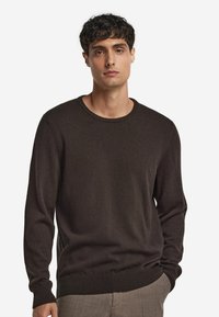 Brązowy sweter dzianinowy z okrągłym dekoltem i długimi rękawami. Ma ryflowane mankiety i dół, gładką teksturę oraz minimalistyczny design.