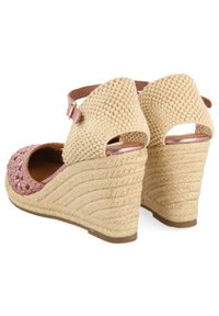 Sandalias con cuña que presentan un upper tejido en beige, un frente trenzado en rosa, una correa de tobillo con hebilla y un detalle de cuerda texturizada en el talón.
