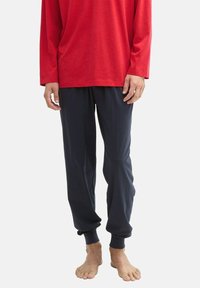 Chemise rouge à manches longues associée à un pantalon bleu foncé à poignet élastique. Les deux vêtements ont une coupe décontractée et sont en tissu léger et doux.