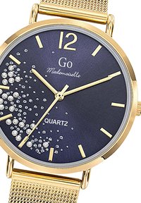Montre en quartz dorée avec un cadran bleu marine, des index dorés et des cristaux décoratifs. Dispose d'un bracelet en métal tressé et d'un boîtier rond.