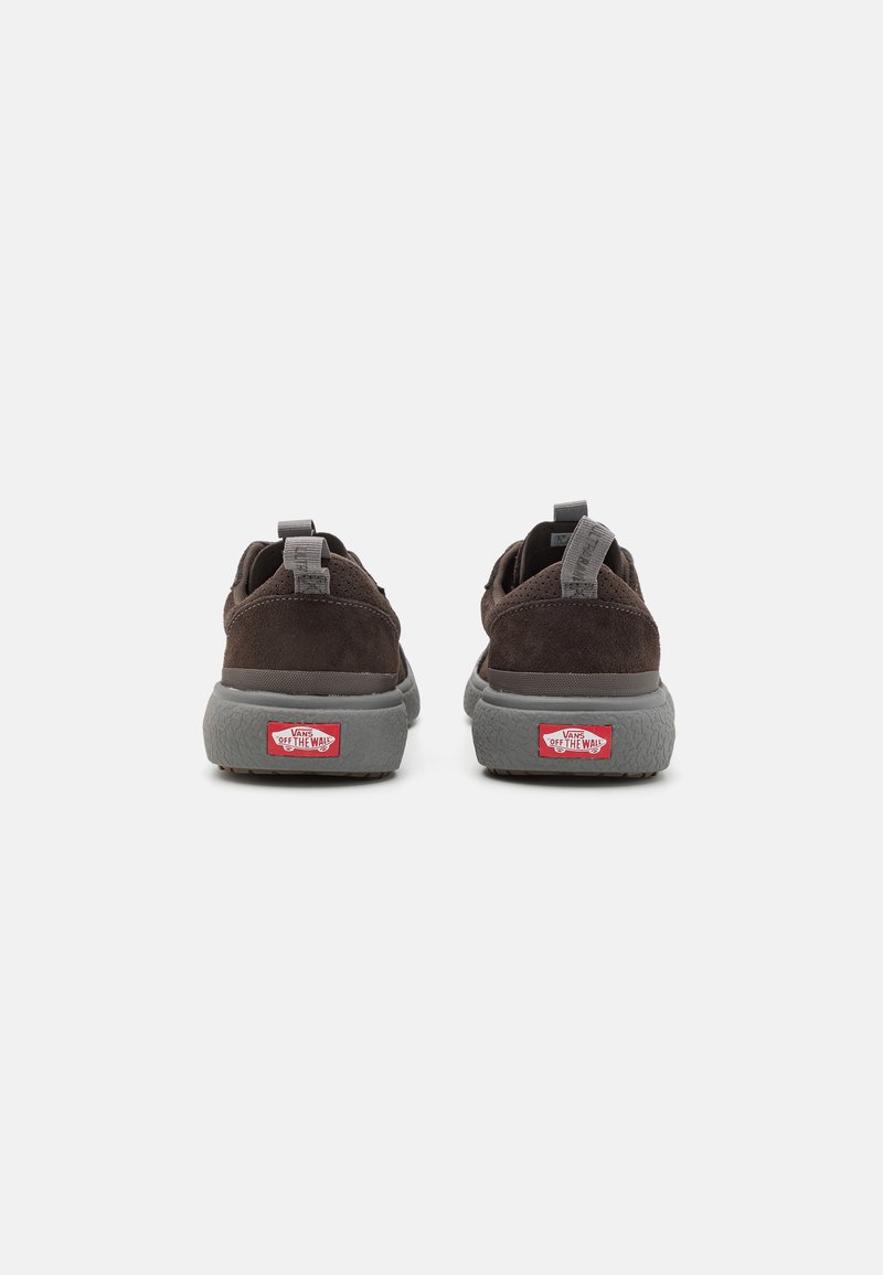 Zapatillas de ante marrón con suelas de goma gris, con un diseño de relieve en la suela y acentos de logo rojo en el talón y el lado lateral.