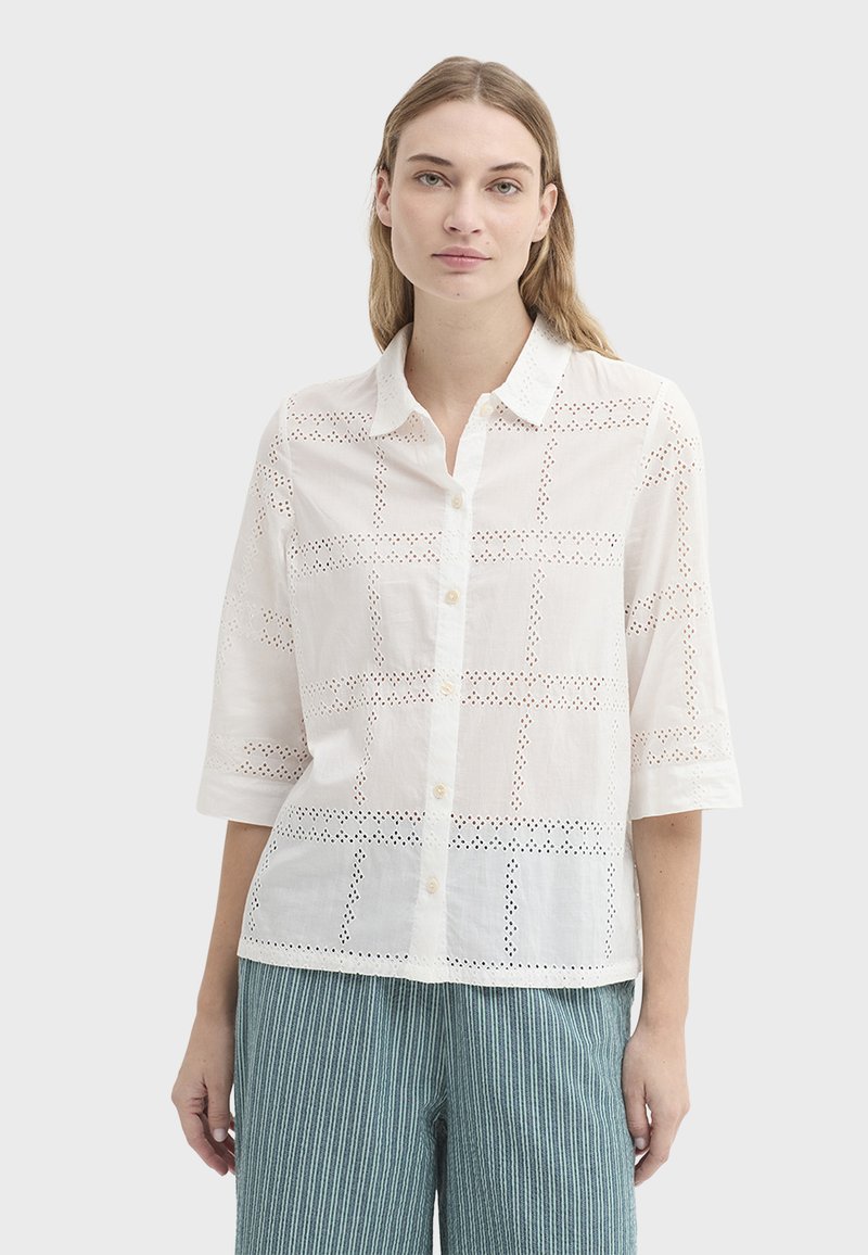 Chemise en coton blanc avec broderie ajourée en motif quadrillé, col, boutonnage sur le devant et manches trois-quarts.