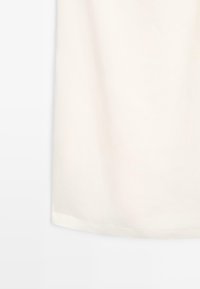 T-shirt à manches courtes de couleur crème en tissu doux avec une texture lisse et un ourlet arrondi, sans motifs ni visuels apparents.