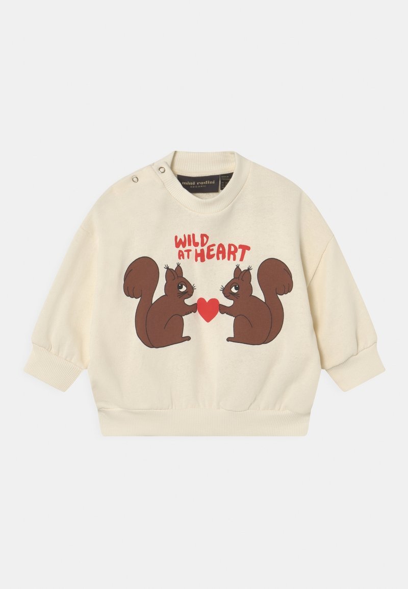 Pull d'enfant couleur crème avec deux écureuils bruns tenant un cœur rouge, et le texte rouge « WILD AT HEART » au-dessus d'eux.