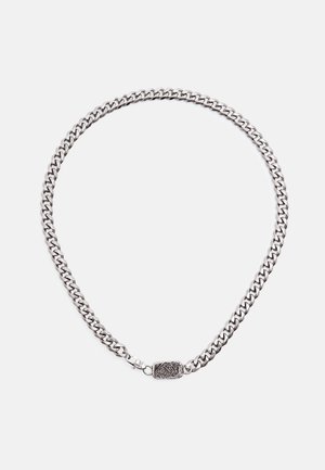 Ezüstlánc nyaklánc vastag szemekkel és téglalap alakú kapoccsal, amelyen gravírozott tigrisfej látható, fehér háttér előtt.