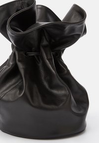 Černá kožená taška s měkkým, nařaseným designem a staženým vrškem, s hladkým povrchem a jemným leskem. Žádné viditelné kovové prvky.