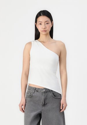 Asymmetrical white tank top made of soft fabric, featuring a single shoulder design and a fitted silhouette, paired with gray trousers.