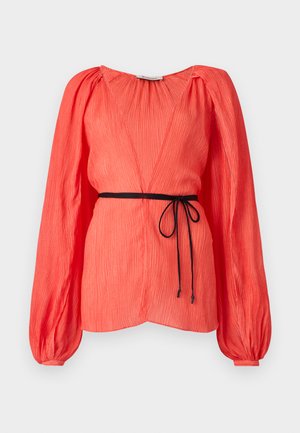 Top cor-de-rosa com decote em V profundo, mangas compridas bufantes e um cinto preto. Tecido texturizado com pregas verticais por todo o lado.