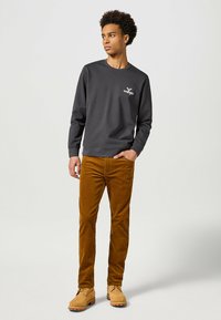 Donkergrijze sweatshirt met een ronde hals en geborduurd logo, gecombineerd met beige corduroy broek en beige laarzen. Gladde textuur, casual pasvorm.