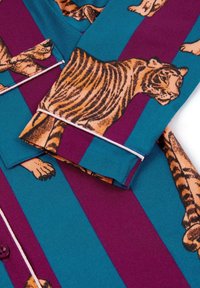 Camicia a maniche lunghe con un motivo a righe turchese e bordeaux, decorata con grandi illustrazioni dettagliate di tigri. Materiale in cotone con chiusura a bottone.