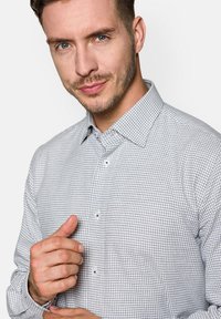 Koszula z długim rękawem w jasnoszary wzór w kratę z granatem, z kołnierzykiem w kształcie stożka i niebieskimi guzikami. Zapinane mankiety i gładka struktura tkaniny.