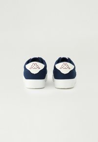 Tênis de lona azul-marinho com sola branca, apresentando um suporte branco no calcanhar e logo vermelho. Tecido texturizado com acabamentos costurados e design plano.