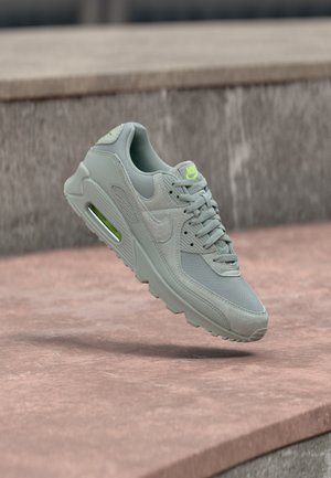 Sivá športová obuv z materiálu sieťoviny a semišu, so svetlou vzduchovou jednotkou, neónovými akcentmi a textúrovanou podrážkou.