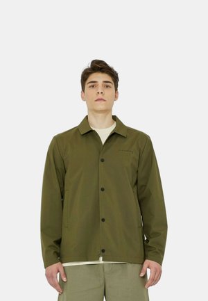 Giacca verde oliva con un design a collo, dotata di una chiusura frontale con bottoni, due tasche laterali e un logo discreto. Tessuto liscio con una vestibilità rilassata.
