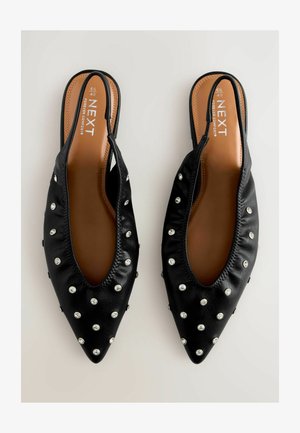 Mustad sünteetilised sussid, millel on terav nina ja ehtena ülemisel osal hõbedased nurgad, mis lisavad ekstra stiili.