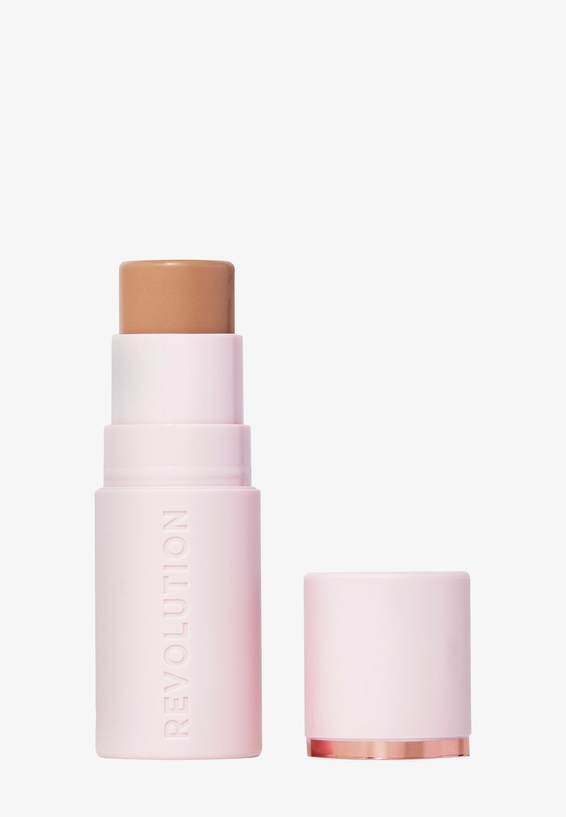 Revolution foundation stick i rosa plastemballasje, med en litt hevet, solid brun topp og et avtakbart lokk med gullakcent.