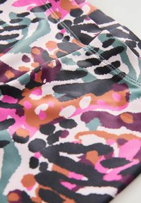 Mångfärgad tyg med ett livfullt djurtryck i rosa, svart, lila och gröna mönster. Mjuk textur och elastiskt material.