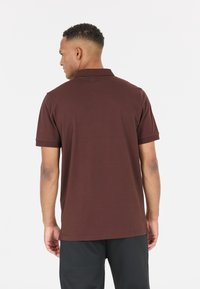 Brun pikétröja med korta ärmar, en standardkrage och rak nederdel, tillverkad av ett mjukt bomullsmaterial med blandning.