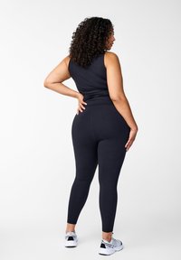 Schwarzes Tanktop- und Leggings-Set aus dehnbarem Material; zeichnet sich durch ein anliegendes Design mit einer glatten Textur und ohne sichtbare Muster aus.