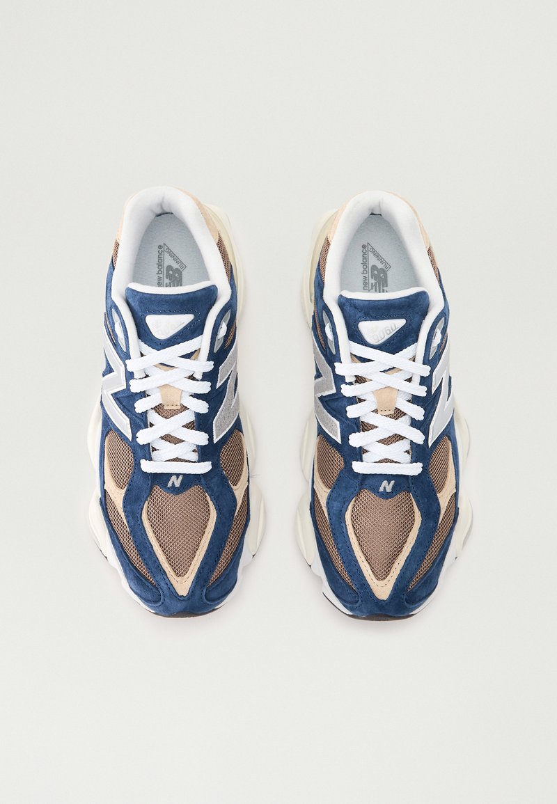 Sportowe sneakersy z niebieską i beżową siateczką, białymi sznurowadłami, wyciszoną podeszwą oraz wyraźnym logo "N" z boku.