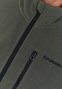 Fleece jacket in dark green with a high collar, featuring a black zipper and embroidered logo. Soft texture with a snug fit.