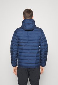 Giacca imbottita blu navy con trapuntatura orizzontale, cappuccio attaccato e texture liscia e lucida. Presenta polsini elastici e orlo dritto.