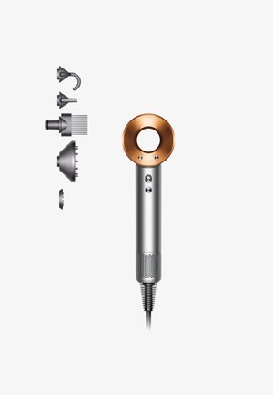 Haartrockner mit silbernem Gehäuse, runder kupferner Düse, mehreren Aufsatzköpfen, seitlichen Tasten und strukturiertem Fuß. Leichtes Design.