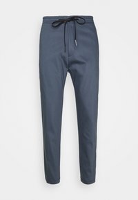 Marinblå joggerbyxor i mjukt tyg, med ett elastiskt midjeband med dragsko, avsmalnande ben och inga synliga fickor.