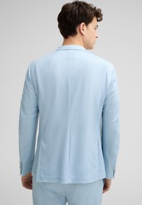 Hellblaues Sakko mit glatter Textur, mit einfachem Schlitz auf der Rückseite und zwei Seitentaschen. Besitzt eine taillierte Passform und Knopfmanschetten.