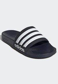 Black slide sandal with a textured footbed, three white stripes on the velcro strap, and an embossed logo. Made from synthetic materials.