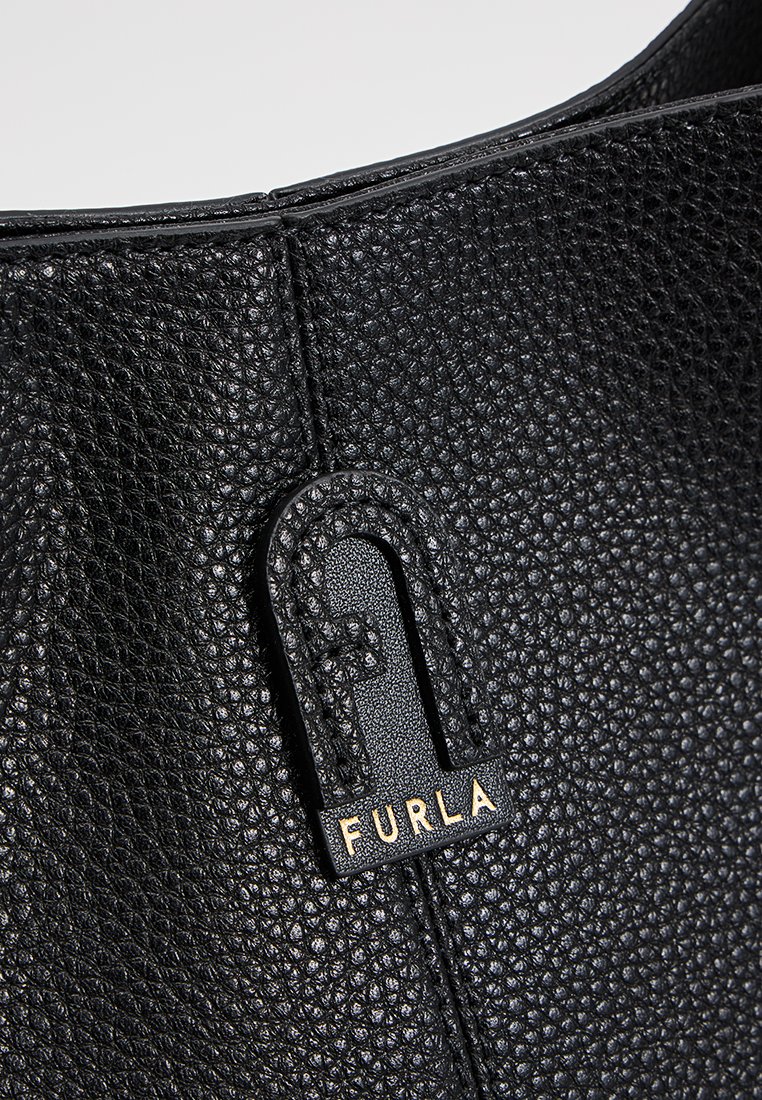 Czarna torebka ze skórzanym wykończeniem o chropowatej fakturze, z wyraźnym złotym znakiem firmowym o charakterystycznym wzorze, podkreślająca jej strukturalny kształt.