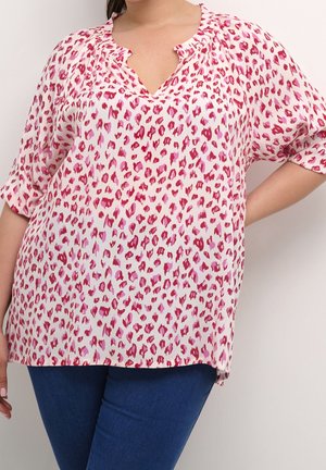 Blouse à imprimé léopard rose et blanc avec un col en V, des manches courtes et des détails froncés au niveau du col. Fabriquée en tissu léger.