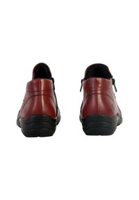 Bottes en cuir rouge à la cheville avec des accents noirs, bout rond et fermetures éclairs à l'arrière. Elles présentent une semelle noire texturée et des détails de couture.