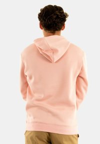 Felpa rosa chiaro con tasca a marsupio e cappuccio regolabile con cordino. Materiale morbido con polsini e orlo a costine. Vista posteriore mostrata.