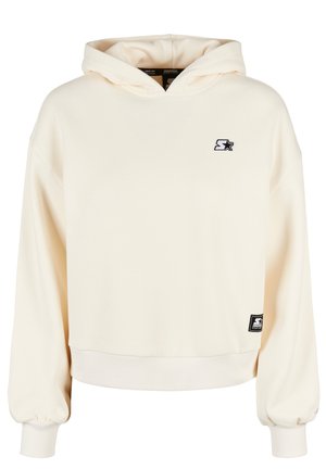 Sweat à capuche de couleur crème en matériau doux. Présente des poignets et un ourlet côtelés, avec un petit logo brodé sur la poitrine.