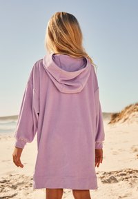 Fliederfarbenes Kapuzensweatshirt mit weiten Ärmeln und lockerem Schnitt, gefertigt aus weichem Stoff, mit Kängurutasche und geripptem Saum.