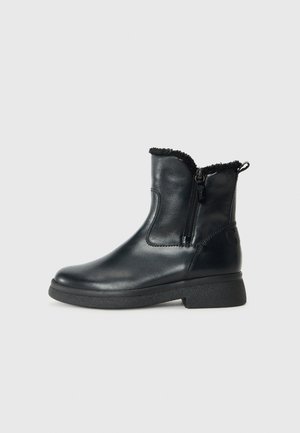 Zwarte leren enkelboots met een gestructureerde rubberen zool, ritssluiting en bontafwerking bij de kraag, met een gladde afwerking en ronde neus.
