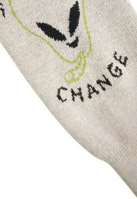Gråstickade strumpor med en aliengrafik i svart och grönt, med ordet "CHANGE" stickat i svart nära tån.